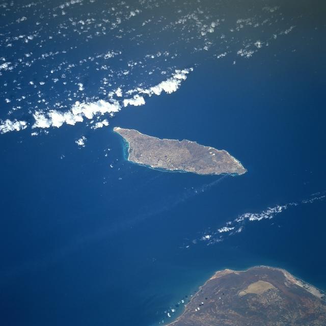 Aruba is a semi-arid island that experiences little variation in temperature throughout the year. Rainfall, which occurs mostly in November and December, averages less than 50 cm (20 in) a year. The red soil on the island is poor and thin and the thorny vegetation is quite drought resistant. Tourism and the refining of oil brought in from nearby Venezuela (whose northern coast appears below) are the major industries. Oraniestad, located on the northwest coast, is the major city of the island. Image courtesy of NASA.