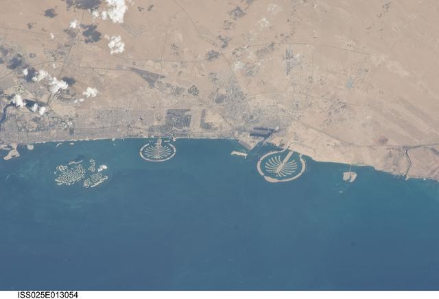 Three man-made archipelagos near Dubai, United Arab Emirates, are featured in this image from the International Space Station (ISS), flying at 350 km (220 mi) above Earth. The municipality of Dubai is the largest city of the Persian Gulf emirate of the same name, and has built a global reputation for large-scale developments and architectural works. Among the most visible of these developments - particularly from the perspective of astronauts onboard the ISS - are three man-made archipelagos. The two Palm Islands - Palm Jumeirah to the left of center, and Palm Jebel Ali, just to the right of center, appear as stylized palm trees when viewed from above. The World Islands (near left edge) evoke a rough map of the world from an air- or space-borne perspective. Image courtesy of NASA.