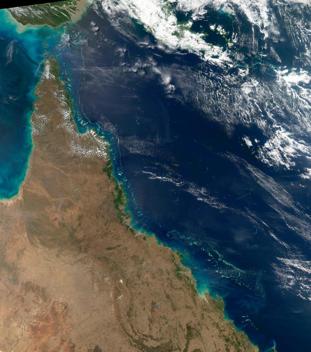 This view of northeast Australia taken by the Aqua satellite vividly shows the many offshore reefs that together form the Great Barrier Reef. The Reef stretches more than 2,000 km (1,240 mi) along the coast of Queensland and is a UNESCO World Heritage Site. Between the reefs and the coastline bands of brown-green "streamers" may be discerned. These are blue-green bacteria (cyanobacteria) that form long overlapping strands and films that can cover immense areas becoming visible even from space. Sailors have long called these brown streamers "sea sawdust." Image courtesy of NASA.