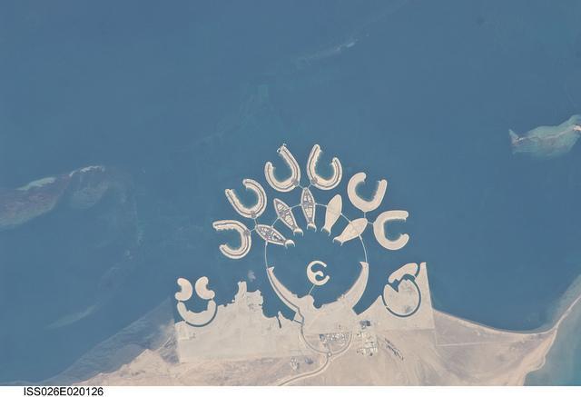 The Durrat Al Bahrain complex is featured in this image photographed from the International Space Station. Set at the southern end of Bahrain Island, at the furthest point from the cities of the kingdom, is this complex of 15 artificial islands designed for residential living and tourism with luxury hotels and shopping malls. Aimed at a cosmopolitan clientele, the Durrat Al Bahrain includes 21 sq km (8 sq mi) of new land for more than 1,000 residences that has been designed as The Islands (six crescent-shaped "atolls" leading off five fish-shaped "petals"). The Crescent at the bottom of the ring is the heart of the complex and features shops, restaurants, hotels, apartments, offices, and schools. The Central Island is dedicated to one, ultra luxurious hotel. The three, thick, crescent-shaped islands at the lower left make up the Durrat Marina; the area between the Marina and the Crescent is a golf course. Image courtesy of NASA.