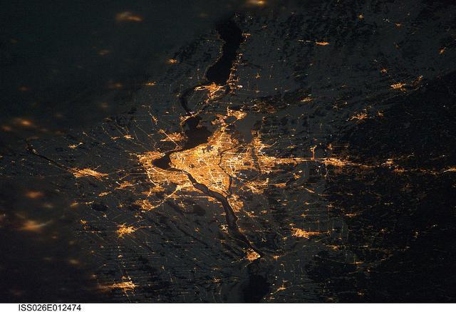A night view of the Montreal metropolitan area is featured in this image from the International Space Station. This photo of the Montreal, Quebec metropolitan area (center) illustrates the extent of urbanization made clearly visible by city lights at night. Major roadways and industrial areas are traced by bright white lighting, while the adjacent residential and commercial land uses are characterized by more diffuse yellow-gold lighting. Rivers and other water bodies appear black, while the surrounding rural countryside is faintly illuminated by moonlight. Blurry areas at top and bottom left are caused by cloud cover. Montreal is the largest city in the dominantly French-speaking province of Quebec, and the second-largest in Canada, after Toronto. While the city of Montreal proper is located on - and almost completely covers - the Island of Montreal at the confluence of the St. Lawrence (center) and Ottawa Rivers (not visible), the city takes its name from Mont Royal located at the city's center. Image courtesy of NASA.