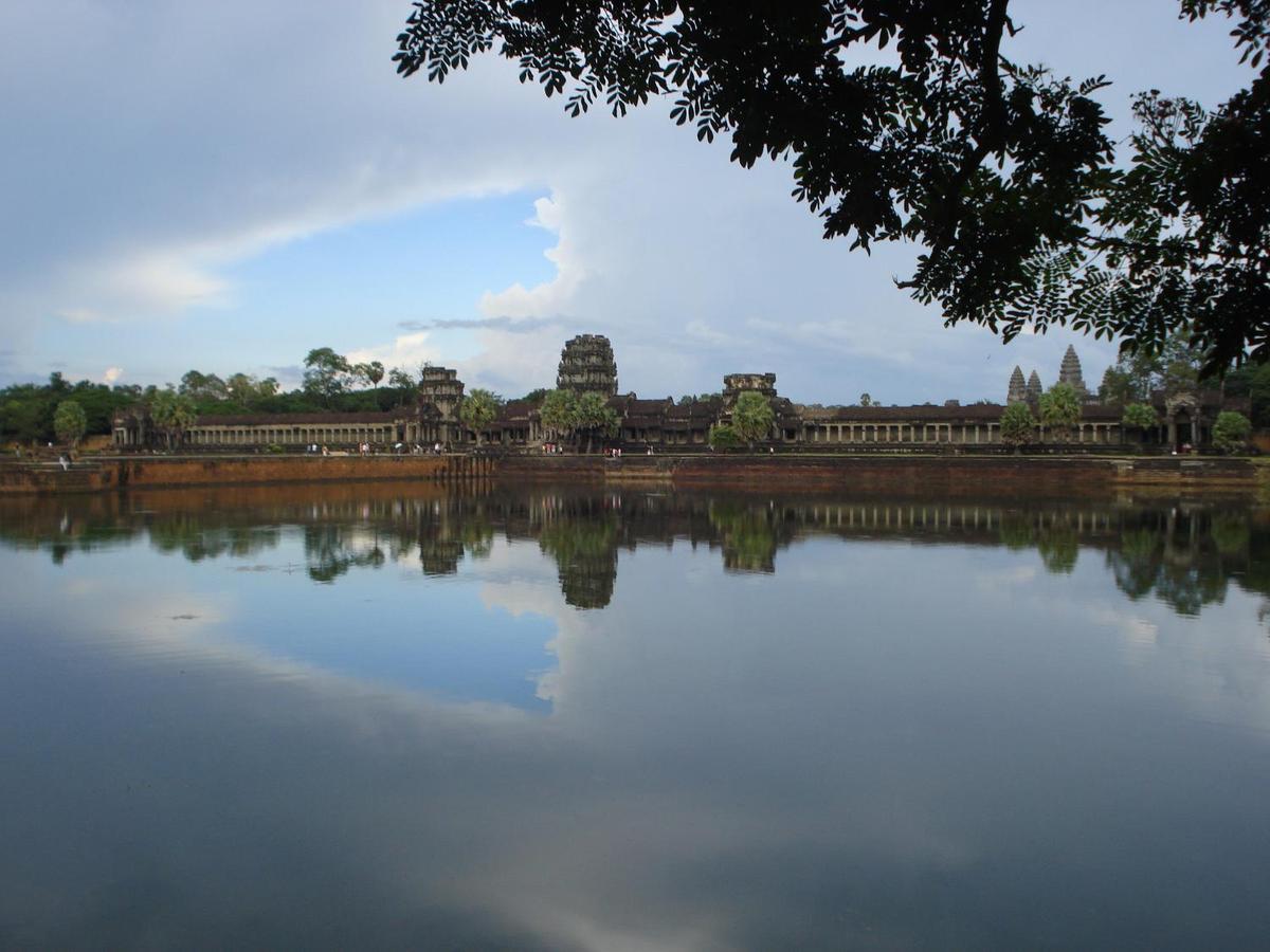 A portion of the sprawling Angkor Wat temple complex as viewed across a moat.