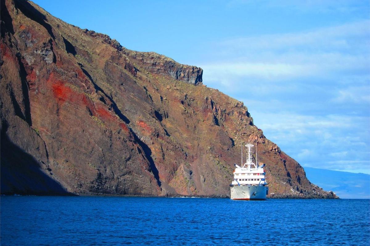 A cruise ship beside a color-streaked cliff in Punta Vicente Roca on Isabela Island.