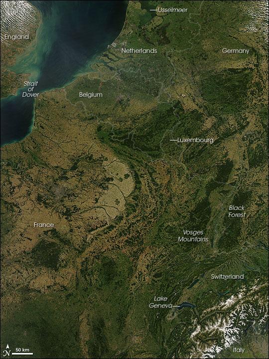 A rare cloud-free view of a wide area of Western Europe. This Aqua satellite image was captured on 30 August 2008. Skies were clear from the Netherlands in the north to Italy in the south, revealing several of Europe's famous natural and man-made features. A few small fires (marked with red dots) were detected, as well.
A pair of geologically matching mountain ranges appear at the border of France and Germany, covered in dark green forests. France's Vosges and Germany's Black Forest rise on either side of the Rhine River Valley. The valley in that area is known to geologists as the Rhine Graben; a graben is an elongated block of Earth's crust that has sunk relative to surrounding blocks. To the south, the snow-covered Alps create an arcing boundary between Switzerland and Italy.
Near the bottom right of the image, one of the largest lakes in Europe, Lake Geneva (formally known as Lac Leman), fills a glacier-carved valley in western Switzerland. This natural lake occurs on the Rhone River, upstream of where it makes a sharp southward bend as it leaves the Alps. At the northern edge of the image is a larger, artificial lake: the Netherland's IJsselmeer. Despite its closeness to the North Sea, IJsselmeer is a freshwater lake. It was originally a saltwater inlet at the mouth of the IJssel River, but in the early 1930s, the Dutch built a dike across the inlet. The freshwater flow of the IJssel River flushed out the seawater, forming the new lake. Photo courtesy of NASA.