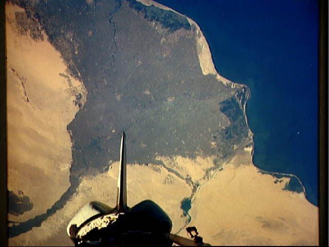 The Nile Delta of Egypt, irrigated by the Nile River and its many distributaries, is some of the richest farm land in the world and home to over half of Egypt's population. The capital city of Cairo lies at the apex of the delta in the lower left. To the west of the river and near the delta apex one can see the three large pyramids and sphinx at Giza. The Suez Canal is just to the right of the delta; the rear of the space shuttle appears in the lower portion of the view. Click on photo for higher resolution. Image courtesy of NASA.