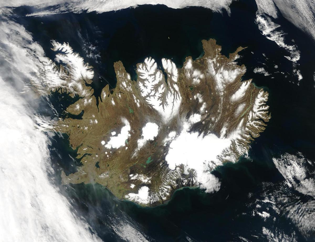 Summer temperatures melt snow and ice on much of Iceland's surface, as shown on this satellite image. The lack of uniform snow cover allows permanent (though shrinking) icefields to show through (particularly Vatnajokull in the southeast), and highlights the island's rugged coastline. Scores of fjords edge the island, resembling feathers waving out into the waters of the northern Atlantic Ocean (bottom) and Greenland Sea (upper left).
Though Iceland's climate is relatively mild and humid thanks to the North Atlantic Drift, and though the island's active volcanism provides inexpensive heating, only about the a quarter of the island is habitable, most of that along the coastlines. Photo courtesy of NASA.