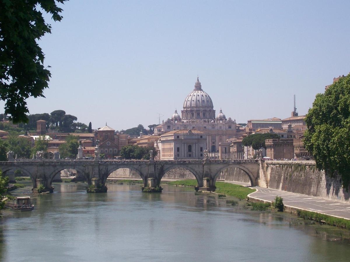 The Vittorio Emanuele Bridge over the Tiber River in Rome with Vatican City in the background. The bridge was completed in 1911.
