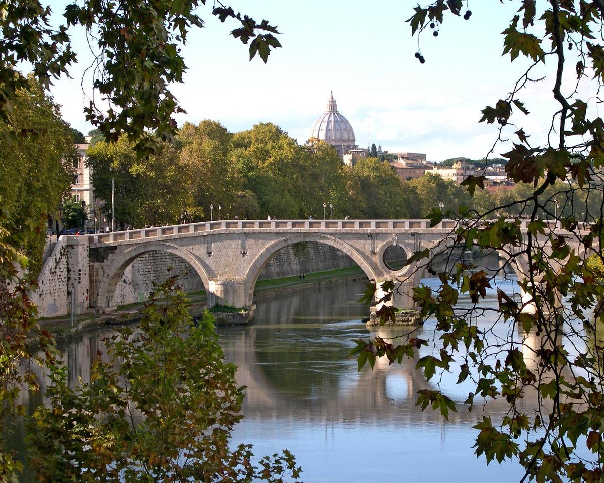 The Garibaldi Bridge over the Tiber River in Rome. The dome of St. Peter's Basilica appears in the background.
