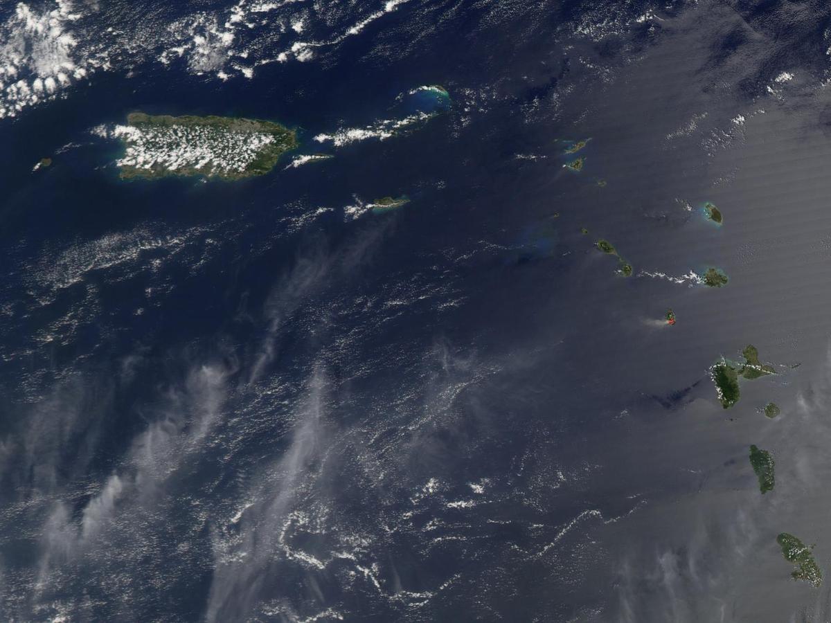 A view of Puerto Rico (upper left) and the isles of the Lesser Antilles. The Soufriere Hills Volcano on the island of Montserrat began emitting steam and ash on 9 February 2006. Low-level activity continued for several days. The volcano produced another plume on 20 March 2006, which is captured on this image. The volcano's pale beige ash plume blows westward over the Caribbean Sea. The red outline shows where the satellite detected a thermal anomaly, an area where the ground surface was significantly hotter than its surroundings. Image courtesy of NASA.