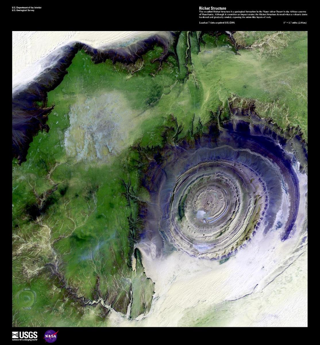 The so-called Richat Structure, center right in this false-color satellite image, is a geological formation in the Maur Adrar Desert. Compare this image to the true-color photo taken from a spacecraft. Although it resembles an impact crater, the Richat Structure formed when a volcanic dome hardened and gradually eroded, exposing the onion-like layers of rock. Image courtesy of USGS.