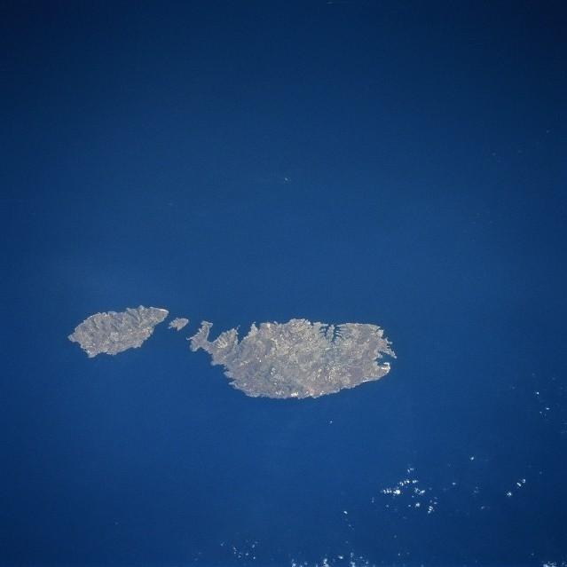 Although small in size (122 sq mi-316 sq km), the independent republic of Malta is strategically located midway between the Strait of Gibraltar and the Suez Canal in the Mediterranean Sea. The country is made up of three inhabited islands that are visible in this image: the island of Malta, the largest, Gozo, and Comino, the smallest (situated between the two larger islands). The capital and largest city, Valletta, is mainly built around a rocky peninsula, arrow-shaped peninsula extends northeast between two natural harbors (small, narrow, dark features). The geological faulting in this area has produced numerous fine natural harbors around the periphery of Malta. Although the islands are composed of sedimentary rocks, mainly limestone and clays, the alkaline soils provide fertile conditions for the well-established agricultural economy. Precipitation amounts can be a problem in that the islands average only about 32 cm (12 in) per year. Malta has few natural resources so the growth of tourism, especially since World War II, has gradually added to the Maltese economy. Photo courtesy of NASA.