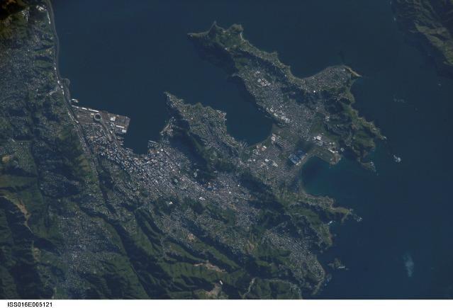 A view of New Zealand's capital of Wellington, located at the southwestern tip of North Island near the Cook Strait. The city is the second largest in New Zealand (after Auckland), and at 41 degrees south latitude, it is the southernmost capital city in the world. Five major geologic faults run through the Wellington municipality. Recognition of the potential seismic hazard in the metropolitan area has led to the adoption of building codes to maximize structural resistance to earthquake damage. Click on photo to increase resolution. Image courtesy of NASA.
