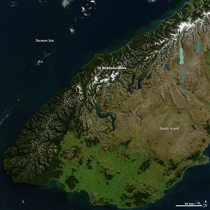 Te Wahipounamu, "the greenstone waters," is a sacred place in the Maori culture of New Zealand. The foreboding mountains and steep-walled valleys on New Zealand's southwest coast are the places of Atua, "the gods." Additionally, the streams that wash down from the glacier-capped peaks carry a highly prized stone, a hard, translucent, green rock that the Maori carved into jewelry and blades, for both tools and weapons. Most New Zealand greenstone is nephrite - a form of jade - though some is bowenite, another mineral. From space, the west coast of New Zealand resembles the greenstone for which it is named. Dark green native forest extends from the mountain tree line to the shore. The forest harbors unique and endangered animals like the kiwi and takahe, both flightless birds, and the kea, the only alpine parrot. The lighter green land in the southeast was once forested, but is now grassland or agriculture. Te Wahipounamu is wilderness, and New Zealand has set the land aside to conserve it. The entire 2.6 million ha (6.4 million acres) that make up the southwest coast of the South Island (about 10 percent of New Zealand's land area) is divided between four national parks, state forests, and other conservation areas. The natural and cultural significance of Te Wahipounamu led UNESCO to declare it a World Heritage area in 1990. Image courtesy of NASA.