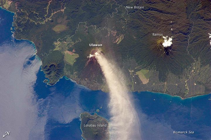 Numerous volcanoes contribute to the landmass of the island of New Britain, the largest in the Bismarck Archipelago of Papua New Guinea. One of the most active of these volcanoes - Ulawun - is also the tallest, with a summit elevation of 2,334 m (7,657 ft).
This astronaut photograph shows a plume of white steam and ash extending from the summit crater of the stratovolcano towards the northwest. The plume begins to broaden as it passes the southwestern coast of Lolobau Island, approximately 23 km downwind. Note that north is towards the lower left.
Ulawun is also known as "the Father," with the Bamus volcano to the southwest also known as "the South Son." The summit of Bamus is obscured by white cumulus clouds (not of volcanic origin) in this image. While Ulawun has been active since at least 1700, the most recent activity at Bamus occurred in the late 19th century. A large region of ocean surface highlighted by sunglint - sunlight reflecting off the water surface - is visible to the north-northeast of Ulawun. Photo courtesy of NASA.