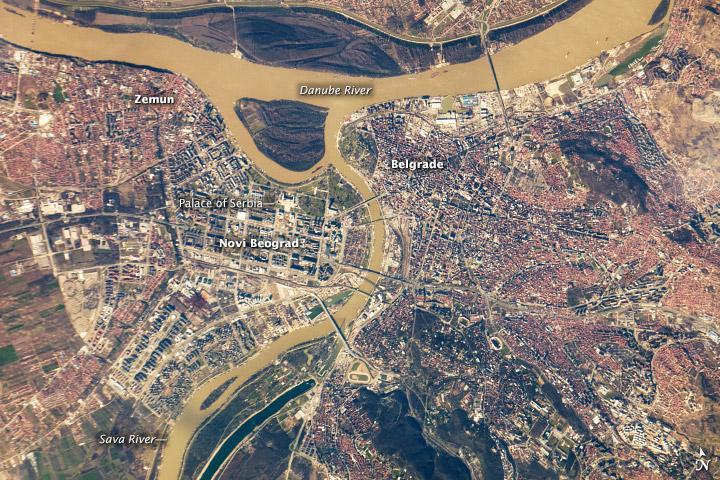 Belgrade, located at the confluence of the Danube and Sava Rivers, is the capital of the Republic of Serbia. The core of old Belgrade - known as Kalemegdan - is located along the right banks of both the Danube and the Sava Rivers (image center). To the west across the Sava, Novi Beograd (New Belgrade) was constructed following World War II. The difference in urban patterns between the older parts of Belgrade and Novi Beograd is striking in this astronaut photograph from the International Space Station. Novi Beograd has an open grid structure formed by large developments and buildings such as the Palace of Serbia - a large federal building constructed during the Yugoslav period, now used to house elements of the Serbian Government. By contrast, the older urban fabric of Belgrade is characterized by a denser street grid and numerous smaller structures.
Other suburban and residential development (characterized by red rooftops) extends to the south, east, and across the Danube to the north. The location of Belgrade along trade and travel routes between the East and West contributed to both its historical success as a center of trade and its fate as a battleground. Today, the city is the financial center of Serbia, while Novi Beograd supports one of the largest business districts in southeastern Europe. Image courtesy of NASA.