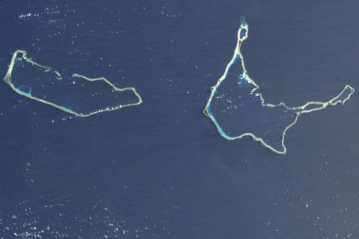 Majuro and Arno Atolls appear as meandering lines of delicate white against a darker ocean background in this satellite image. Areas of shallow water near the shore appear iridescent blue, especially in the southwest portion of each atoll and off the northwest tip of Arno Atoll. Overhead, tiny white clouds dot the sky. Majuro Atoll is 40 km (25 mi) in circumference, and it partially encloses a lagoon of nearly 300 sq km (115 sq mi). The lagoon is far bigger than the atoll itself, whose land area is less than 10 sq km (4 sq mi); walking from the lagoon side to the ocean side of the atoll takes only minutes. Neighboring Arno Atoll encloses three lagoons: two "pinched lagoons" in the northeast and northwest, and a main lagoon of nearly 340 sq km (130 sq mi). Arno's total land area is just 13 sq km (5 sq mi). Scientists have long understood that coral atolls develop around volcanic islands and remain there after those islands have eroded away. To what extent the final shape of an atoll is influenced by wind and ocean wave activity, however, remains a topic of debate. Image courtesy of NASA.