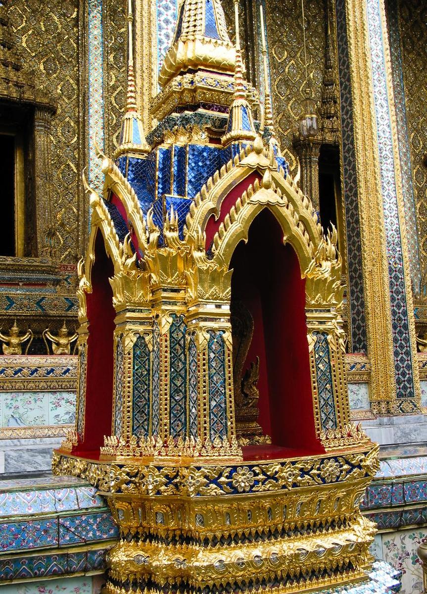 At the Grand Palace in Bangkok; the Palace complex features brightly colored buildings, golden spires, and glittering mosaics. This close-up highlights the widespread and effective use of mirrored tiles in the construction process.