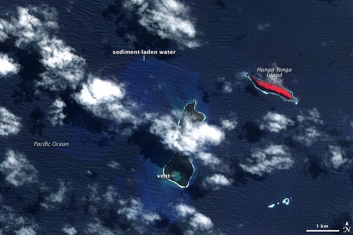 In mid-March 2009, a plume of ash and gas burst out of the ocean as an undersea volcano began to erupt in the South Pacific nation of Tonga. Small sections of the rim of the large volcano had been above water, forming the islands of Hunga Tonga and Hunga Ha'apai (center). The eruption occurred at two vents, one submerged and the other on Hunga Ha'apai. The eruption pumped out enough rock and ash that by 25 March, when NASA's Terra satellite captured this image, the submerged vent was surrounded by new land.
The new land is the dark mass south of Hunga Ha'apai. It was not present in an earlier image taken on 14 November 2006 (next photo). In this image, clouds cover the space between the new land and Hunga Ha'apai, but the new land connects Hunga Ha'apai with the underwater vent, essentially enlarging the small island. The vent itself is the nearly perfectly circular hole near the southern edge of the new land.
Also revealed are some of the other impacts of the eruption. The ocean around the erupting volcano is bright blue, likely colored with ash, rock, and other volcanic debris. The eruption killed or damaged plants on Hunga Ha'apai. In this false-color image, plant cover is red. In 2006, Hunga Ha'apai had supported vegetation, but after the eruption, the island was black. Either the plants were buried in ash or dead in the wake of the eruption. Photo courtesy of NASA.