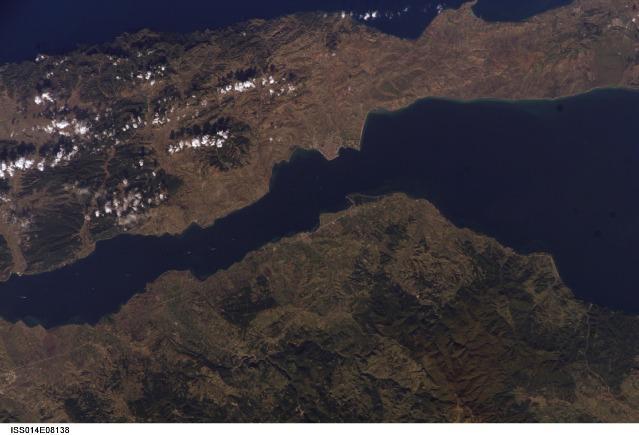 The city of Gallipoli (Gelibolu in Turkish; light gray to pink area in center of photo) sits at a crossroads between the Sea of Marmara (to the right) and the Dardanelles Strait (which leads to the Aegean Sea). Water in the Strait flows in both northeast and southwest directions due to opposite surface and undercurrents. Several ships are visible in the Strait to the southwest of Gallipoli (center left). Image courtesy of NASA.
