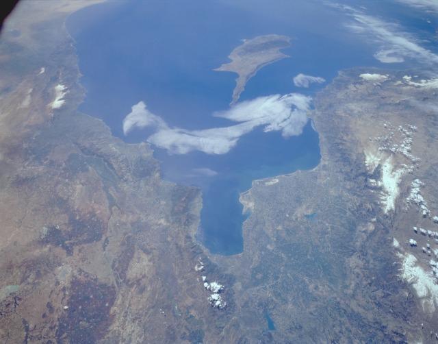 A southwest-looking photograph of south-central Turkey and northwest Syria. The Plain of Adana, an extensive agricultural region, is located northwest of the Gulf of Iskenderun (the roughly rectangular-shaped gulf near the center of the photo) and is irrigated by the Seyhan River. Adana, the largest city in the region, can be seen midway between the Gulf and the Taurus Mountains to the west. The coastlines of Syria, Lebanon, and Israel are visible along the eastern Mediterranean Sea. The island of Cyprus can be seen off the Turkish and Syrian coasts. Photo courtesy of NASA.