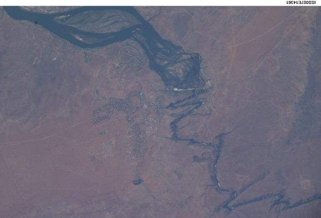 Victoria Falls and the Zambezi River as seen from space. The Zambezi flows southeast in a wide bed before plunging suddenly 108 meters over the Victoria Falls into a narrow gorge. The falls and their famous spray clouds are 1.7 km (1.1 mi) long during flood season, the longest sheet of falling water in the world. The falls appear as a ragged white line in this image. The small town of Victoria Falls in Zimbabwe appears just west of the falls, with smaller tourist facilities on the east bank in Zambia. Image courtesy of NASA.