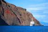 A cruise ship beside a color-streaked cliff in Punta Vicente Roca on Isabela Island.