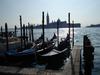 A view of San Giorgio Maggiore Island in Venice across the sparkling waters of the lagoon with gondolas in the foreground.