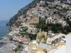  View of the city of Positano on the rugged Amalfi Coast showing the church Our Lady of the Assumption in the foreground and homes built vertically on a cliff in the background.
