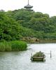 Layers of green foliage along the shoreline of a Japanese garden.
