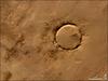 Deep in the Sahara lies a crater, a nearly a perfect circle that is 1.9 km (1.2 mi) wide, and sports a rim 100 m (330 ft) high. The Tenoumer crater sits in a vast plain of rocks so ancient they were deposited hundreds of millions of years before the first dinosaurs walked the Earth. Close examination of the structure has revealed that the crater's hardened "lava" was actually rock that had melted from a meteorite impact.
On this satellite image the crater's outline is unmistakable, yet it does not necessarily look like a crater; the light and shadows make it look more as if someone pressed a giant cookie cutter into the rock. In this image, the sunlight shines from the southeast (lower right), and the bright arc along the northwestern part of the crater is where the crater walls slope up to the rim. Around the perimeter, the relatively steep walls cast dark shadows. Although it resides in ancient rock, Tenoumer is geologically young, ranging in age between roughly 10,000 and 30,000 years old. Photo courtesy of NASA.