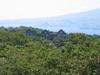A view of Topside - the highest area of Corregidor - taken from the vicinity of the Spanish Lighthouse. Shown are the remains of the &quot;Mile-Long Barracks&quot; barely visible above the trees. These main barracks on the Topside section housed the troops of the coast artillery battalions who manned the island defenses. The building was a three-story concrete structure designed to be hurricane proof while providing comfortable, airy accommodations in a tropical environment. Despite the fact it never was a mile long when built, the structure was considered the longest barracks in the world. In the background, across the North Channel, are the mountains of Bataan Peninsula overlooking Corregidor.