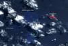 In mid-March 2009, a plume of ash and gas burst out of the ocean as an undersea volcano began to erupt in the South Pacific nation of Tonga. Small sections of the rim of the large volcano had been above water, forming the islands of Hunga Tonga and Hunga Ha'apai (center). The eruption occurred at two vents, one submerged and the other on Hunga Ha'apai. The eruption pumped out enough rock and ash that by 25 March, when NASA's Terra satellite captured this image, the submerged vent was surrounded by new land.
The new land is the dark mass south of Hunga Ha'apai. It was not present in an earlier image taken on 14 November 2006 (next photo). In this image, clouds cover the space between the new land and Hunga Ha'apai, but the new land connects Hunga Ha'apai with the underwater vent, essentially enlarging the small island. The vent itself is the nearly perfectly circular hole near the southern edge of the new land.
Also revealed are some of the other impacts of the eruption. The ocean around the erupting volcano is bright blue, likely colored with ash, rock, and other volcanic debris. The eruption killed or damaged plants on Hunga Ha'apai. In this false-color image, plant cover is red. In 2006, Hunga Ha'apai had supported vegetation, but after the eruption, the island was black. Either the plants were buried in ash or dead in the wake of the eruption. Photo courtesy of NASA.