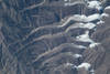 Glaciers in the Qilian Mountain range of central China as viewed from the International Space Station at an altitude of about 400 km (250 mi). The icy tongues extend to the left from the higher elevations at the right. Image courtesy of NASA.